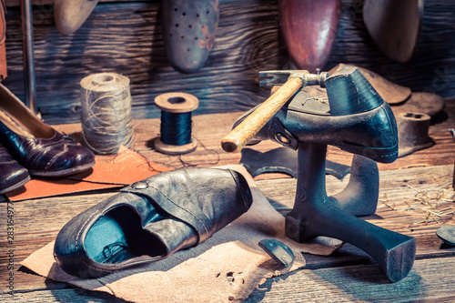 Closeup of vintage shoemaker workshop with tools and shoes photo