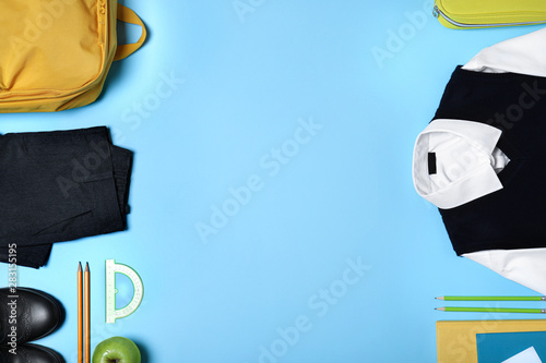 Flat lay composition with school uniform on blue background. Space for text