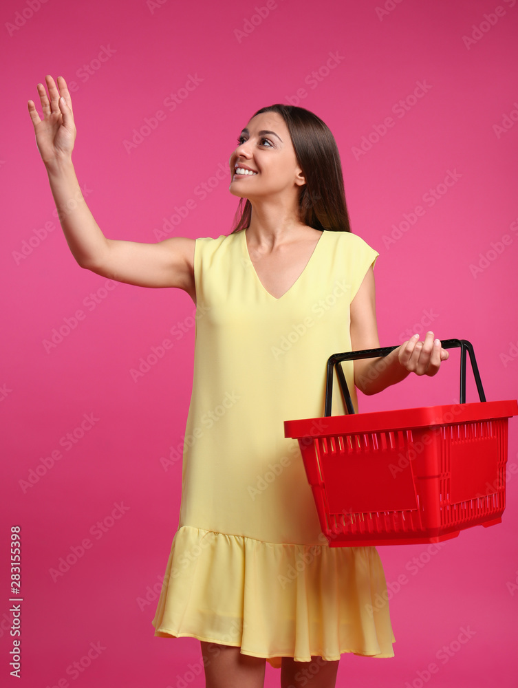 Young woman with empty shopping basket on pink background Young woman with empty shopping basket on pink background