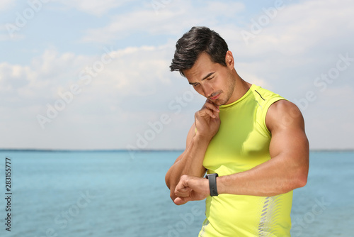 Young man checking pulse after training on beach. Space for text