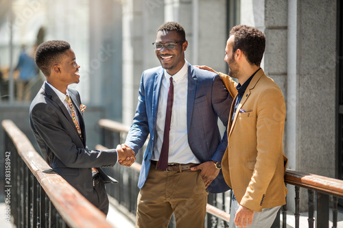three handsome adult men in suits communicate