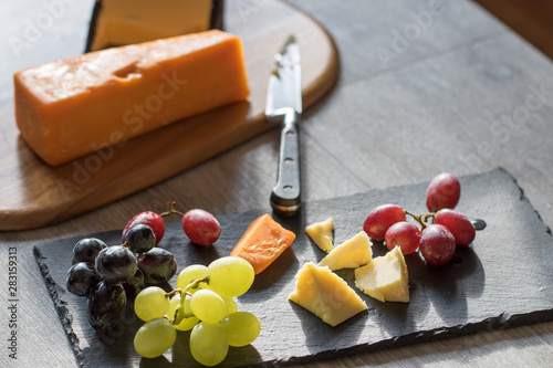 Fototapeta Red and white hard cheese selection with grapes. Rustic food.