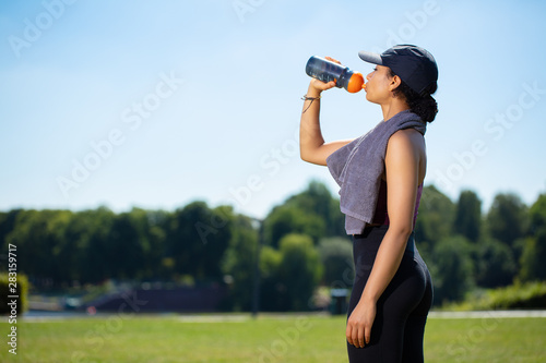 young woman drinking water from bottle after an outdoor sport session