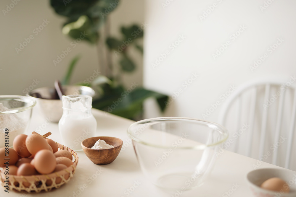 Horizontal shot of serious male wearing beige apron breaking egg into metal bowl Horizontal shot of serious male wearing beige apron breaking egg into metal bowl