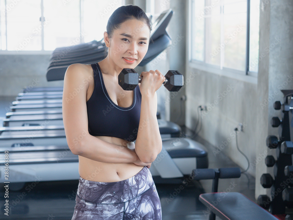 asian woman is exercising with a dumbbell in gym asian woman is exercising with a dumbbell in gym