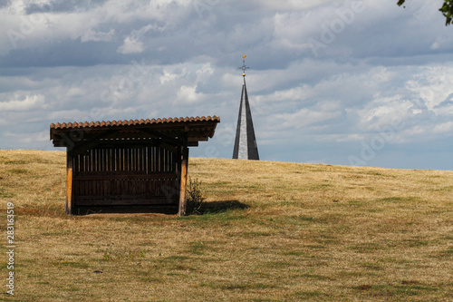 Church tower behind a field with a shelter photo