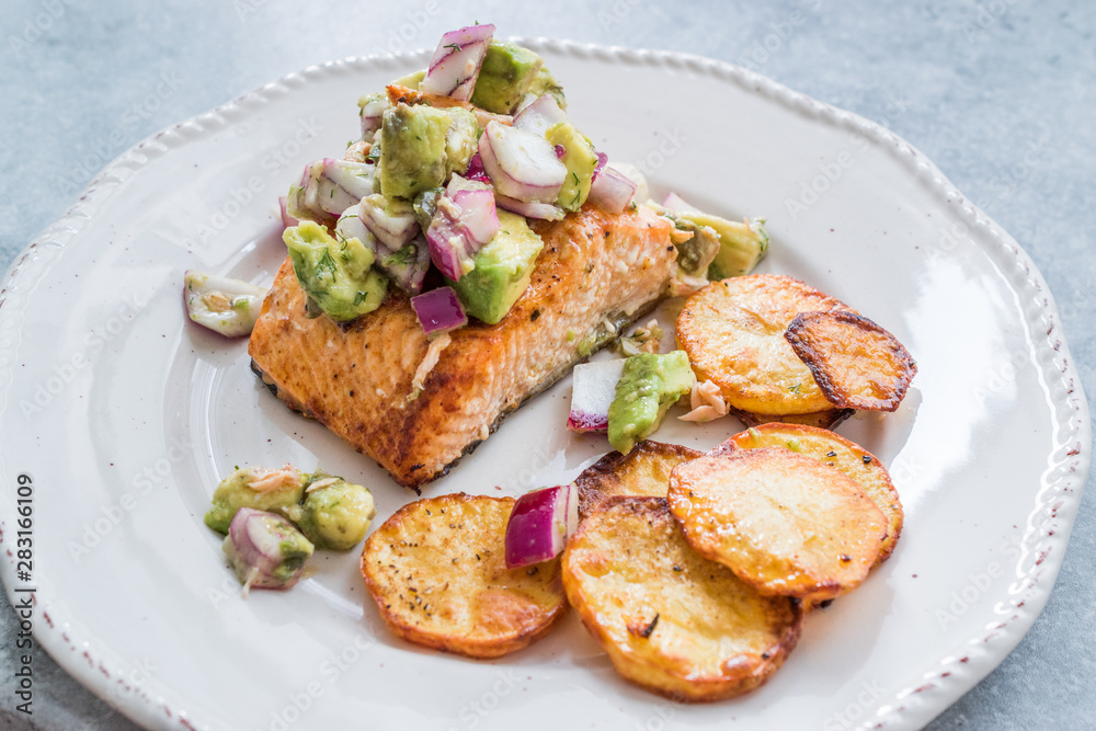 Salmon Fish Fillet with Avocado, Red Onions and Baked Round Potato Slices in Seafood Plate. Salmon Fish Fillet with Avocado, Red Onions and Baked Round Potato Slices in Seafood Plate.