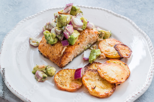 Salmon Fish Fillet with Avocado, Red Onions and Baked Round Potato Slices in Seafood Plate.