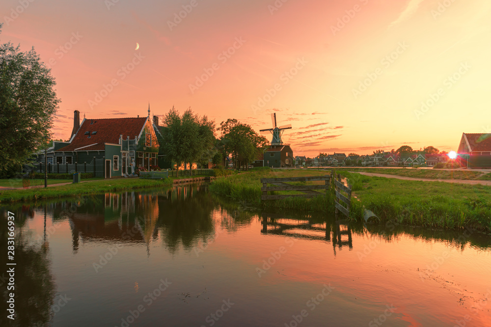 Fototapeta premium Sunset over the Zaanse Schans calm and flat canal water