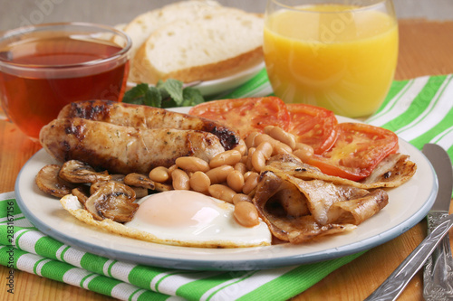 Classic English breakfast served: eggs, bacon, beans, juice and tea