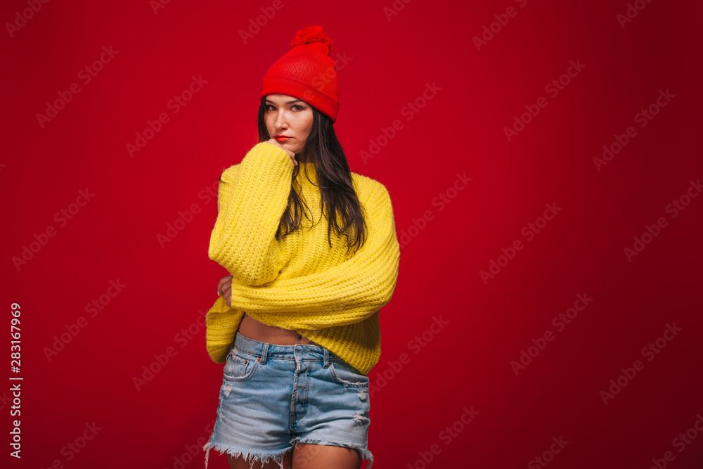 Girl in yellow sweater and hat on red background Girl in yellow sweater and hat on red background