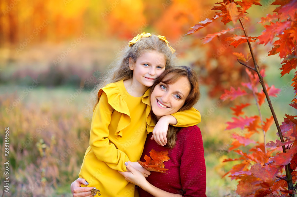 Happy family resting in a beautiful autumn park on a background of bright foliage