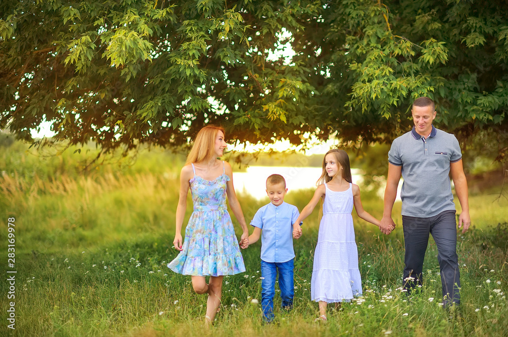 portrait of a happy family outdoors, holding hands walk in the park at sunset, the family spends time together