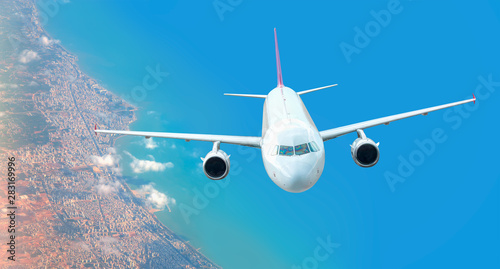 Commercial white Airplane Flying Over City and Blue sea