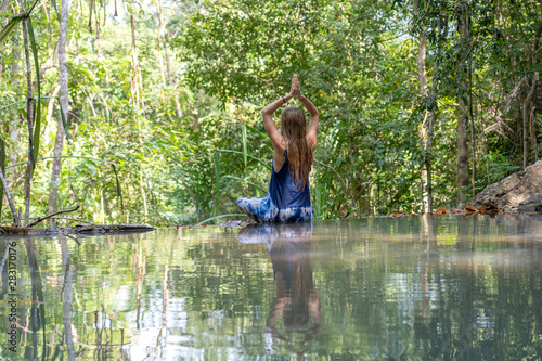 Fototapeta Naklejka Na Ścianę i Meble -  Beautiful woman practicing yoga near turquoise water of cascade waterfall at deep tropical rain forest, island Koh Phangan, Thailand