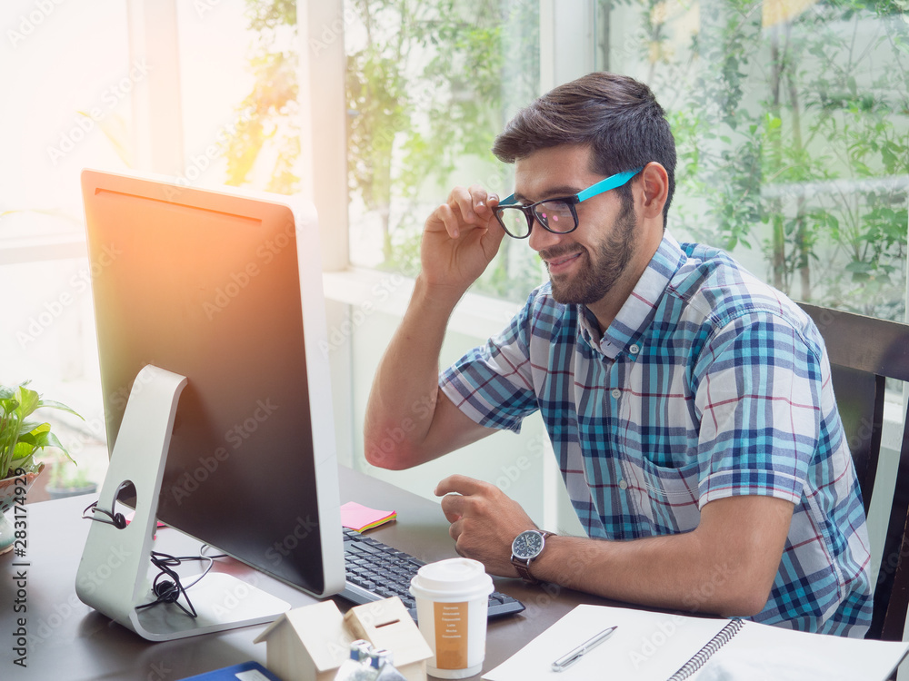 young man working at home with glasses and smile ,businessman works on his computer to get all his business