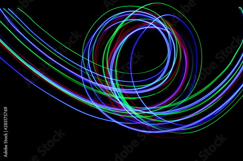 Long exposure, light painting photography. Vibrant streaks of neon multi color against a black background.