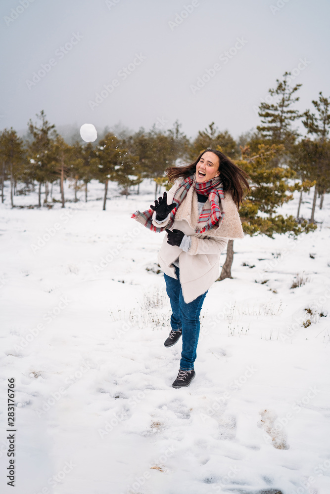 Joyful woman dressed in a coat, throwing snowballs - Vacation concept