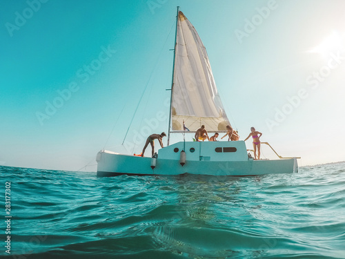 Group of friends having fun sailing around the sea - Young people enjoying summer tour vacation - Soft focus on guys silhouettes - Travel and fun concept - Fisheye lens distortion