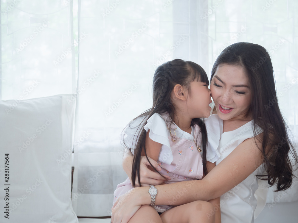 The child is playing in bed with her mother,.Mom is hugging her daughter and kiss cheek in bed. The child is playing in bed with her mother,.Mom is hugging her daughter and kiss cheek in bed.