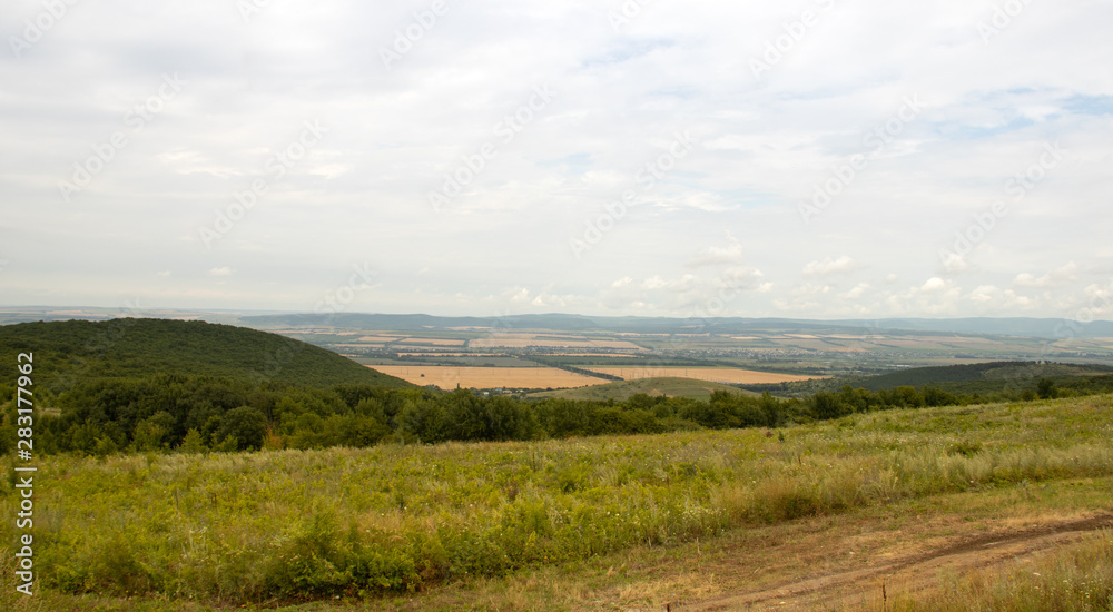 Southern highlands. Field with low mountains. Low mountains with trees. Anapsky district, Russia. Summer mountain landscape