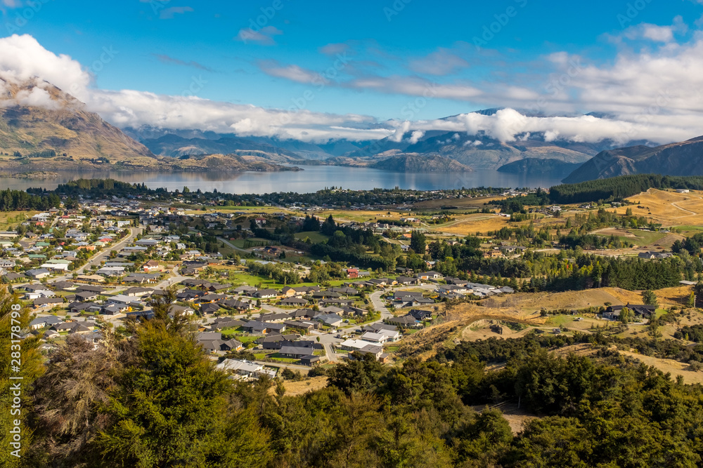 A view from the top of Mt Iron trail, overlooking the valley, fields, houses and mountains next to Lake Wanaka, New Zealand