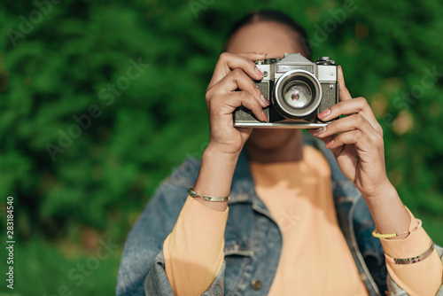 Young african american woman making photo at old camera