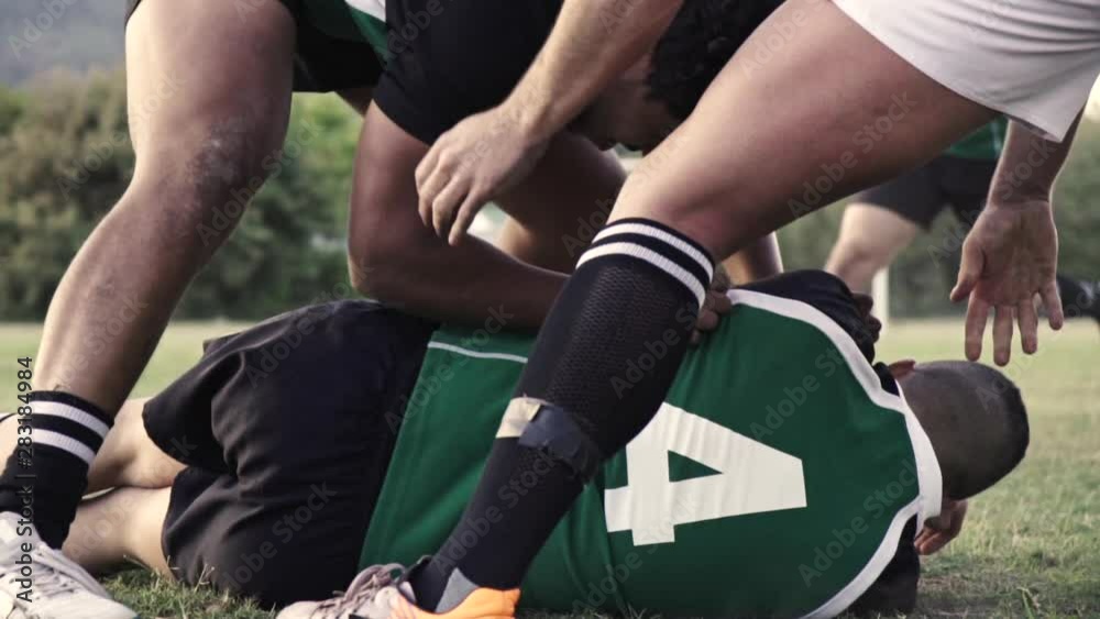 Rugby players in action to get the possession of the ball during the match. Rugby player is blocked by the opponent team player on ground to get the ball. Rugby players in action to get the possession of the ball during the match. Rugby player is blocked by the opponent team player on ground to get the ball.