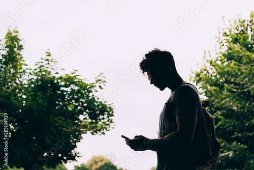 side view of man with backpack using digital device outside