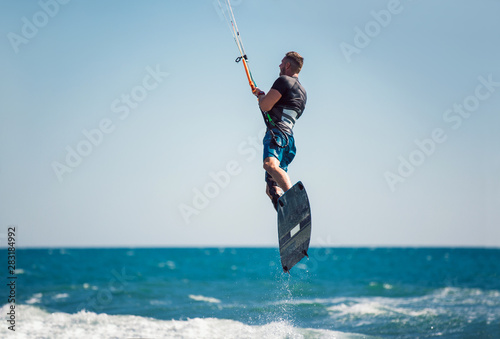 Professional kiter makes the difficult trick on a beautiful background. Kitesurfing Kiteboarding action photos man among waves quickly goes