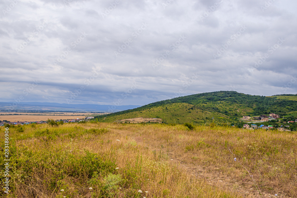 Southern highlands. Field with low mountains. Low mountains with trees. Anapsky district, Russia. Summer mountain landscape Southern highlands. Field with low mountains. Low mountains with trees. Anapsky district, Russia. Summer mountain landscape