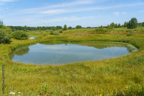 round lake among floodplain meadows and forests © vredaktor