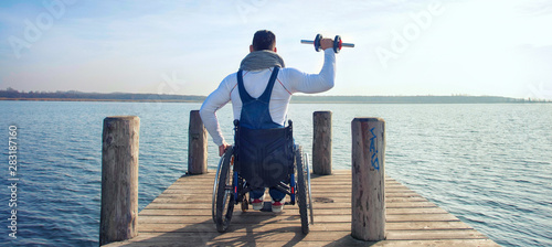 Rollstuhlfahrer mit Hanteln am See