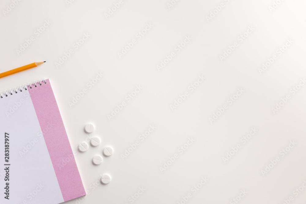Notepad, pencil and pills on white background. Medical concept. Flat lay. Notepad, pencil and pills on white background. Medical concept. Flat lay.