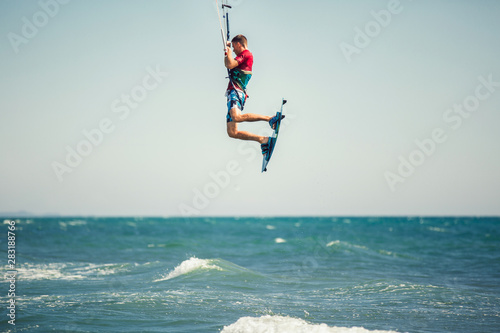 Professional kiter makes the difficult trick on a beautiful background. Kitesurfing Kiteboarding action photos man among waves quickly goes
