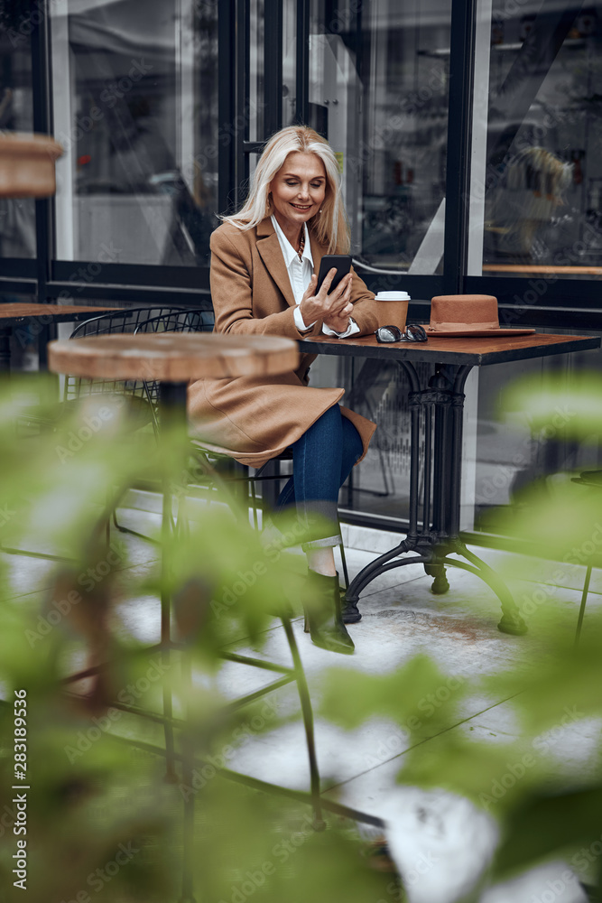 Glad woman using smartphone and smiling stock photo Glad woman using smartphone and smiling stock photo