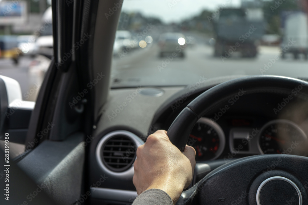 Car on the road. Black car interior. Dashboard, male hand on a steering wheel, speedometer. 