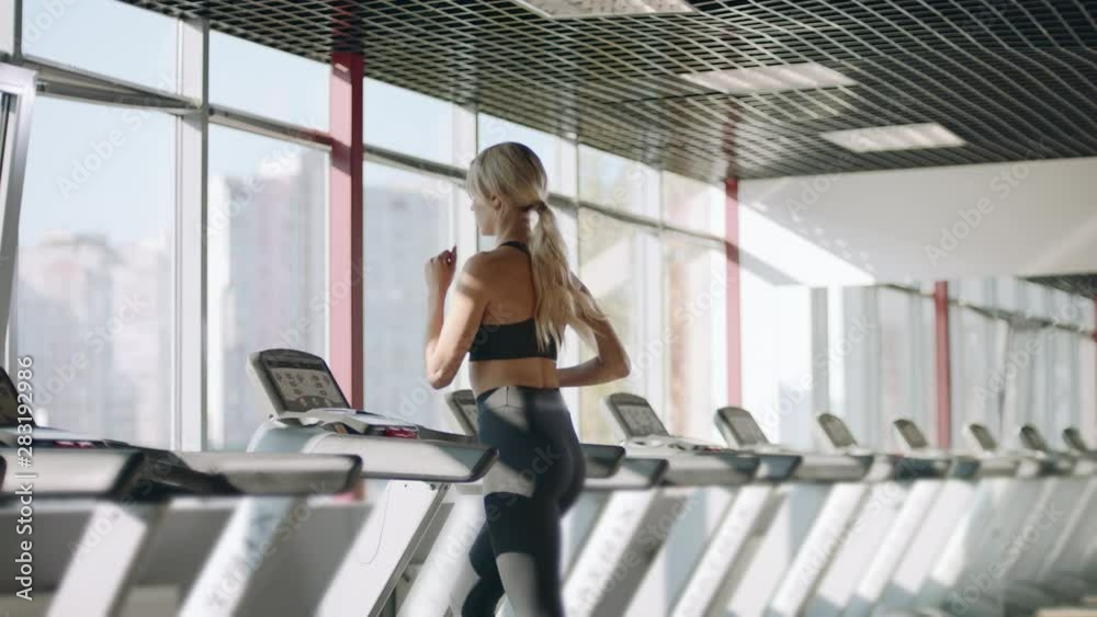 Fitness woman running on treadmill in gym. Pretty girl having cardio training.