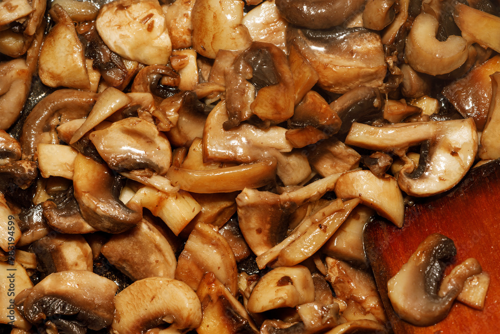 Fried champignon mushrooms in a pan closeup background texture Fried champignon mushrooms in a pan closeup background texture