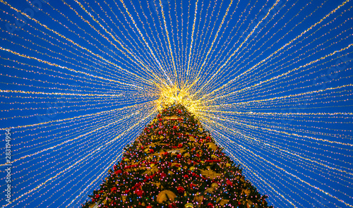 Christmas tree with lights decorations outdoors at night. New Year Celebration. Luxury decorated in european city street at winter seasonal holidays.