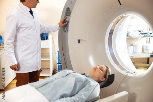 Lady lying on CT scanner bed during tomography test in hospital