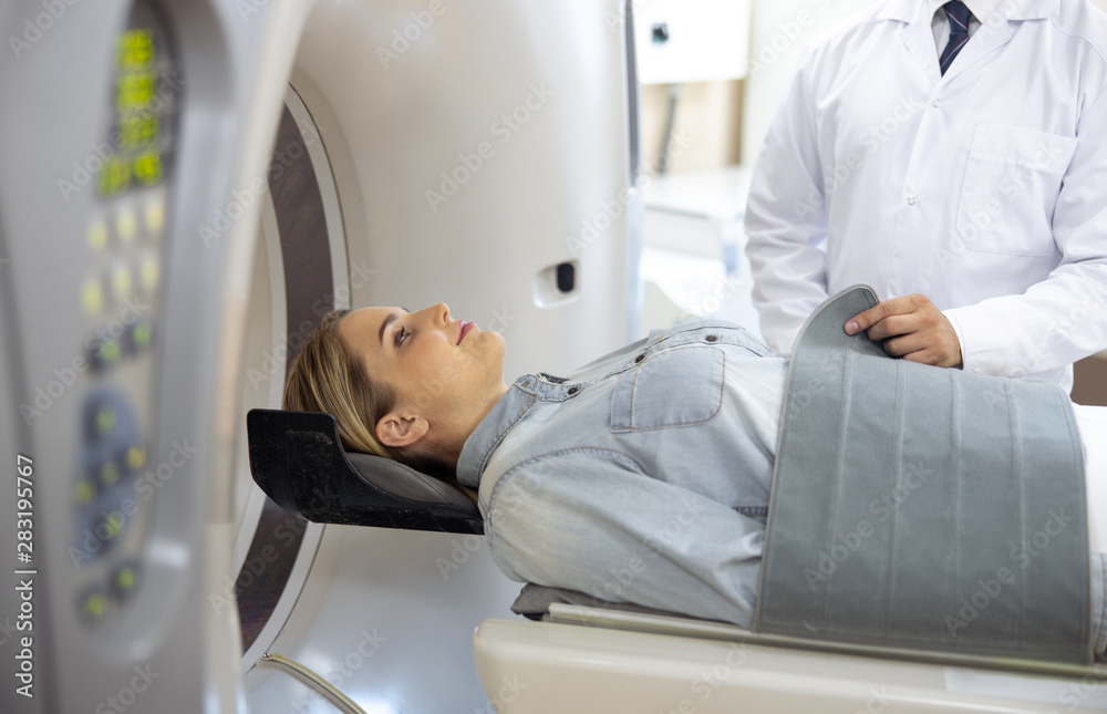 Doctor preparing young lady for CT scan