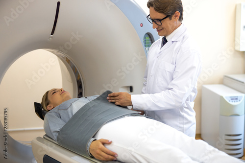Smiling doctor putting immobilizing belt on patient before CT scan