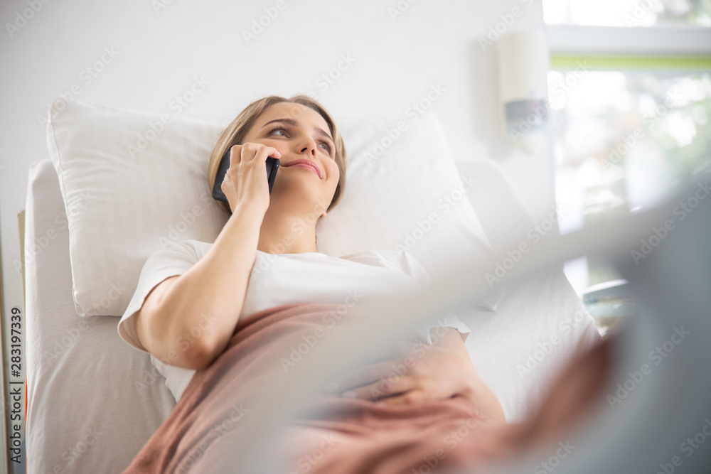 Smiling pretty girl talking on cellphone in hospital room Smiling pretty girl talking on cellphone in hospital room