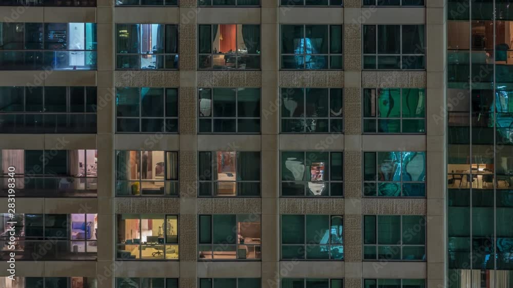 Glowing windows of the multi-storey building with lighting inside and moving people in apartments timelapse. Aerial view of modern residential skyscrapers in Dubai greens district Glowing windows of the multi-storey building with lighting inside and moving people in apartments timelapse. Aerial view of modern residential skyscrapers in Dubai greens district