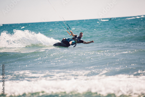 Kitesurfing. Man rides on kite on waves