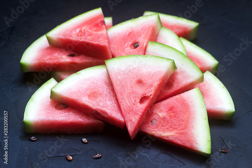 Triangular watermelon slices with seeds on a black concrete background. photo