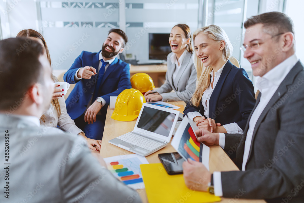 Obraz premium Group of cheerful dedicated Caucasian architects working on project together. Boardroom interior.