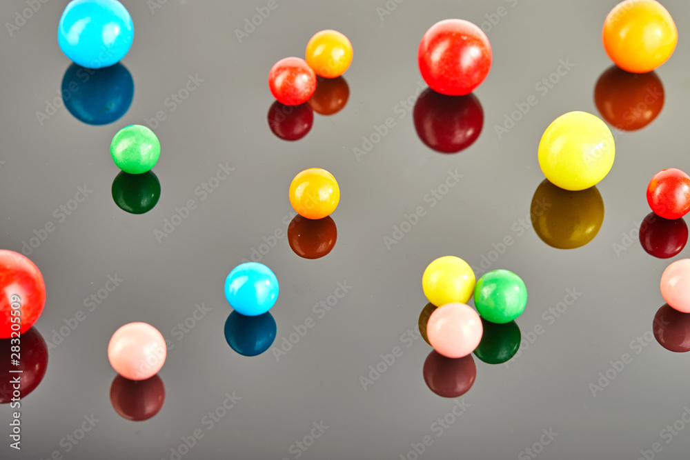 Multi colored balls of chewing gum on a gray background with reflection.
