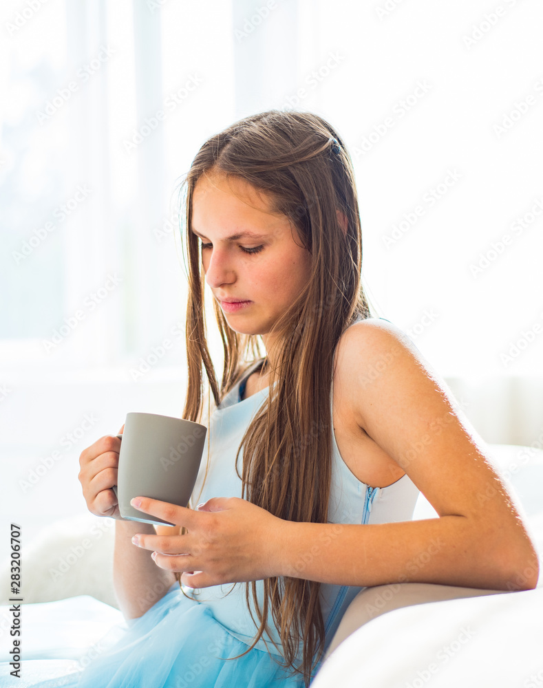 portrait of young teenager brunette girl with long hair sitting on sofa with cup at home portrait of young teenager brunette girl with long hair sitting on sofa with cup at home